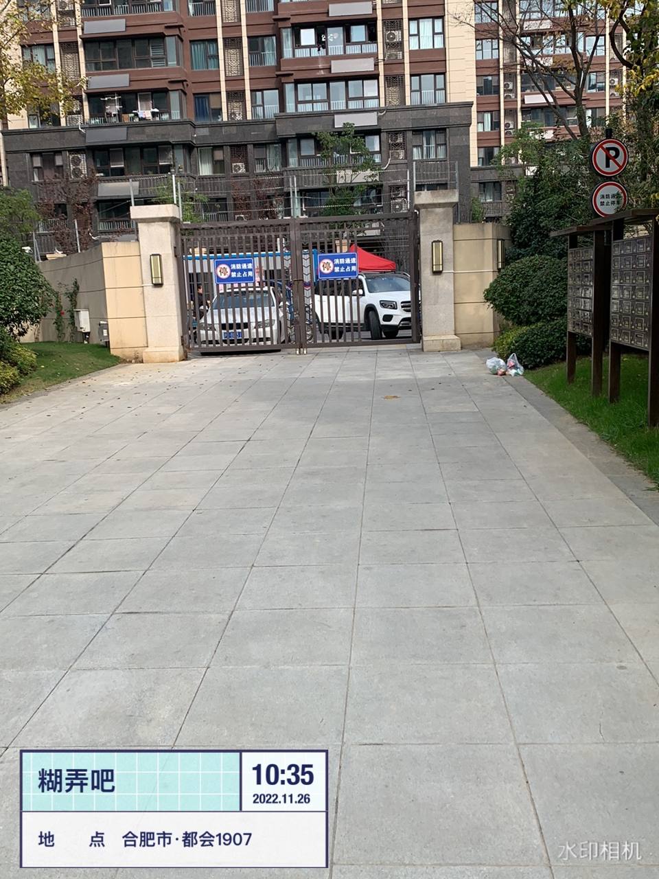 消防通道铁门前停放机动车并悬挂"消防通道禁止占用"标识且旁有垃圾杂物